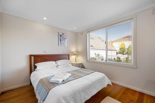 a white bedroom with a bed and a window at Waters Edge in Frankston