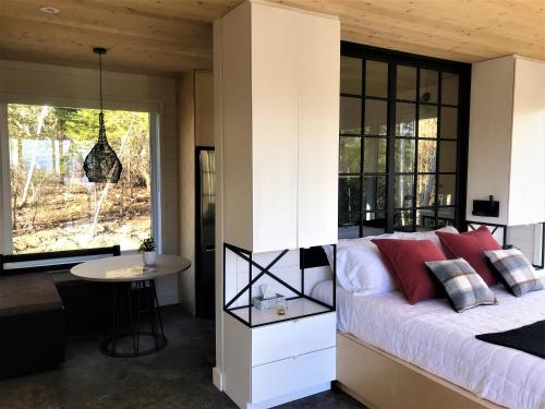 een slaapkamer met een bed met rode kussens en een tafel bij Charlevoix expérience thermale en pleine nature - Suites Nature Charlevoix - Suite #2 in Les Éboulements