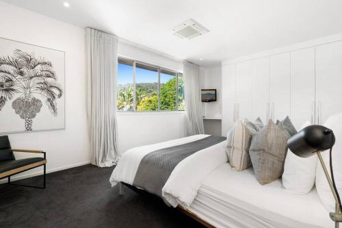 a white bedroom with a bed and a window at Witta Circle - Walk to Hastings St & Noosa Beach in Noosa Heads