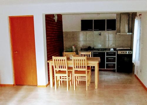 uma cozinha com uma mesa de madeira e cadeiras num quarto em Duplex Esquel em Esquel