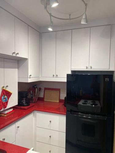 a kitchen with white cabinets and a black refrigerator at Beach Front Condo in Isla Verde! in San Juan