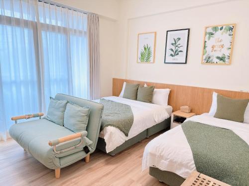 um quarto com 2 camas e uma cadeira em Gardenstay em Luodong