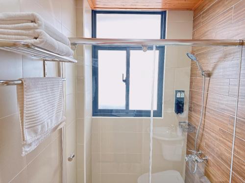 a bathroom with a shower and a toilet and a window at Gardenstay in Luodong