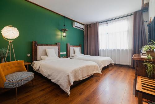 two beds in a room with a green wall at 张家界天门山伴田居民宿 in Zhangjiajie