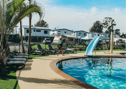 une personne se promenant près d'une piscine avec toboggan dans l'établissement Jervis Bay Holiday Park, à Huskisson