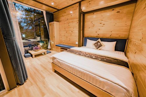 ein Schlafzimmer in einem Blockhaus mit einem Bett und einem Fenster in der Unterkunft Dragon Dalat Villa in Da Lat