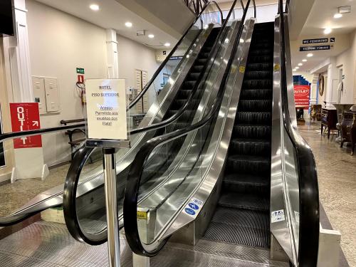 an escalator in a shopping mall with a sign at Flat Centro de Capivari in Campos do Jordão
