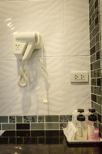 a white phone hanging on a wall in a bathroom at Embryo Hotel  in Pattaya Central