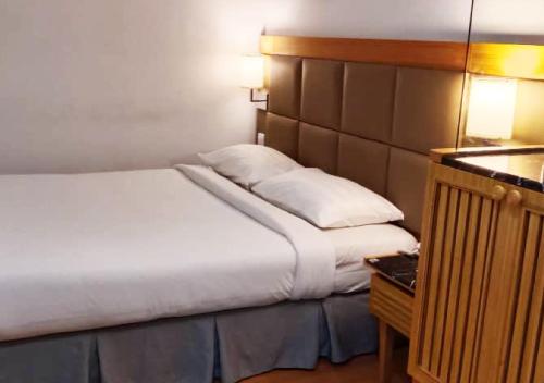 a bedroom with a large bed and a night stand at Crown Garden Hotel in Kota Bharu