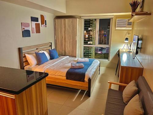 ein Schlafzimmer mit einem Bett mit blauen Kissen und einem Fenster in der Unterkunft Highview IT Park in Cebu City