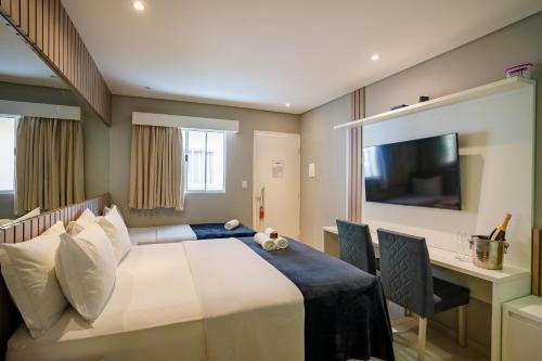 a bedroom with a bed and a desk and a television at POUSADA HAPPY DAY PARATY in Paraty