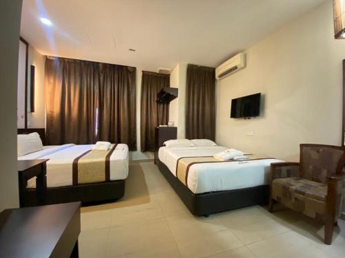 um quarto de hotel com duas camas e uma secretária em D&F BOUTIQUE HOTEL SENAWANG em Senawang