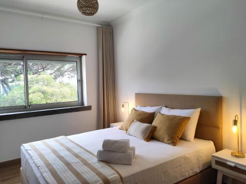 a bedroom with a bed with two pillows and a window at Embaixada da Vila in Cascais