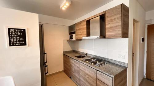 a kitchen with wooden cabinets and a counter top at machado apartamentos moron in Morón