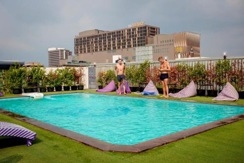 two men standing next to a large swimming pool at Embryo Hotel  in Pattaya Central