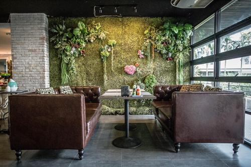 a restaurant with couches and a table and plants on the wall at Embryo Hotel  in Pattaya Central