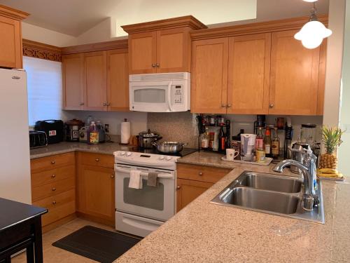 a kitchen with a sink and a stove and microwave at Ko Olina Ocean View Home Office in Kapolei