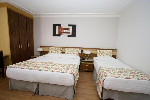 a hotel room with two beds and a sink at Laguna Plaza Hotel in Brasilia