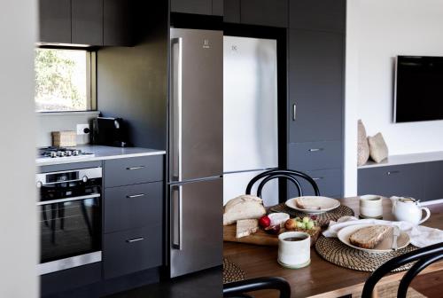 a kitchen with a wooden table and a refrigerator at Carinya Byron Bay in Hayters Hill