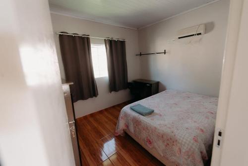 um pequeno quarto com uma cama e uma janela em casa em LAGES 2 km do centro LAGES em Lages