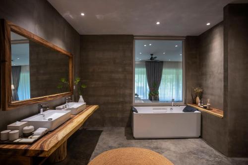 a bathroom with two sinks and a tub and a window at Farmhouse Resort & Spa in Kampong Chhnang