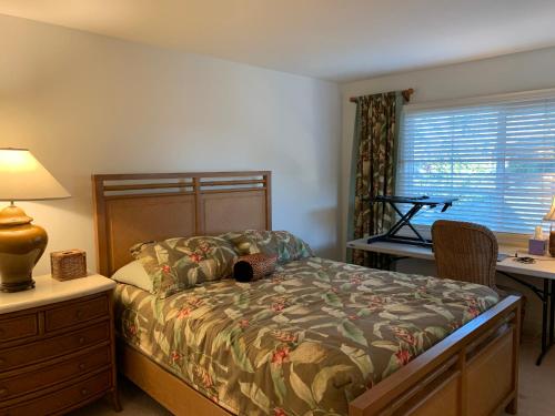 a bedroom with a bed and a desk with a lamp at Ko Olina Ocean View Home Office in Kapolei
