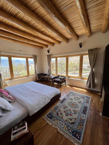 a bedroom with a large bed and large windows at Heschuk Guest House in Leh