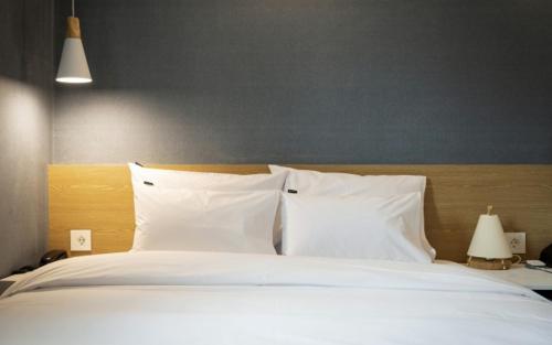 a bed with white sheets and pillows in a bedroom at Hotel Yaja Gwangalli in Busan