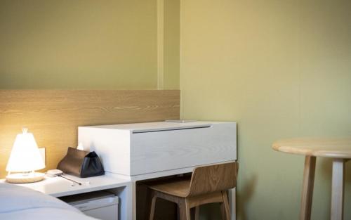 a desk with a lamp and a chair next to a bed at Hotel Yaja Gwangalli in Busan