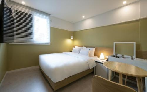 a bedroom with a bed and a desk with a computer at Hotel Yaja Gwangalli in Busan