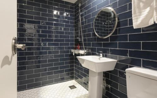 a blue tiled bathroom with a sink and a toilet at Hotel Yaja Gwangalli in Busan