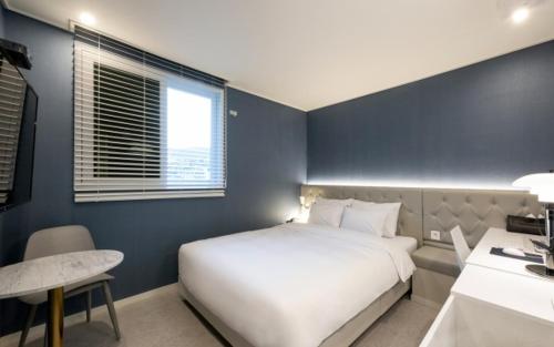 a bedroom with a large white bed and a desk at Hotel Yaja Gwangalli in Busan