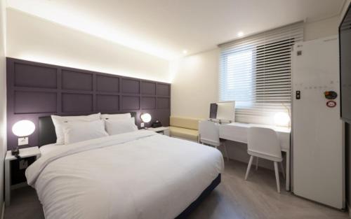 a bedroom with a large white bed and a table at Hotel Yaja Gwangalli in Busan
