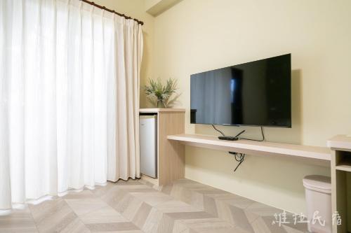 a room with a flat screen tv on a wall at 台東市區維拉包棟民宿 附廚房及電動麻將 in Taitung City