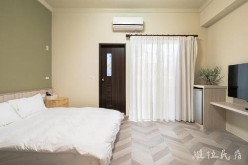 a bedroom with a white bed and a television at 台東市區維拉包棟民宿 附廚房及電動麻將 in Taitung City