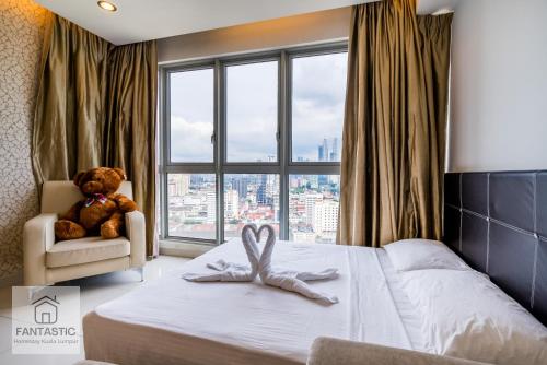 ein Schlafzimmer mit einem Bett mit einem Teddybär und einem Stuhl in der Unterkunft Regalia Residence @ KLCC View Sky Pool by MC in Kuala Lumpur