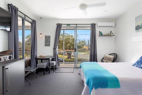 a bedroom with a bed and a table and a balcony at Scarborough beach break holidays - Unit 2 in Scarborough