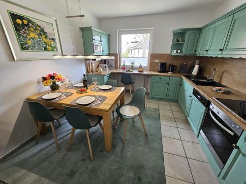 a kitchen with green cabinets and a wooden table and chairs at Ferienhaus Distelfink entspannen in der Mitte von Deutschland in Gudensberg