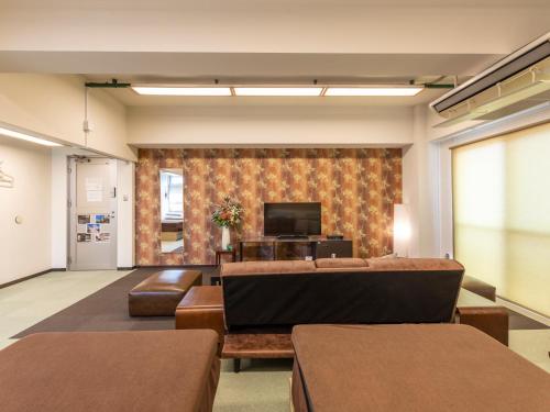 a waiting room with a couch and a tv at Omotenashi Hostel Miyajima in Hatsukaichi