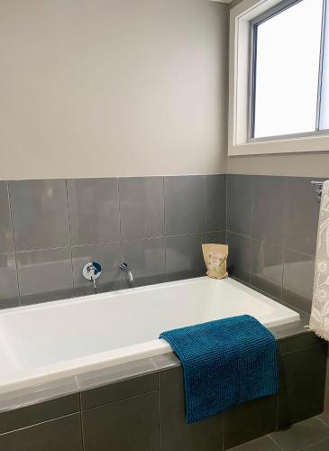 a bath tub in a bathroom with a blue towel at GARDEN CUBBY - The Lakeside Haven in Lake Illawarra