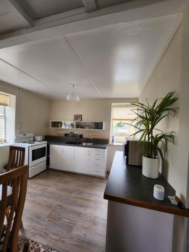 una cocina con armarios blancos y una mesa con una planta en Caithness en Roxburgh