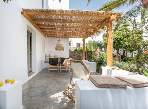 an outdoor patio with a wooden pergola and chairs at Levantes House Mykonos in Ano Mera