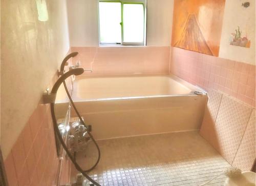 a bath tub in a bathroom with pink tile at 民宿かず in Sosa