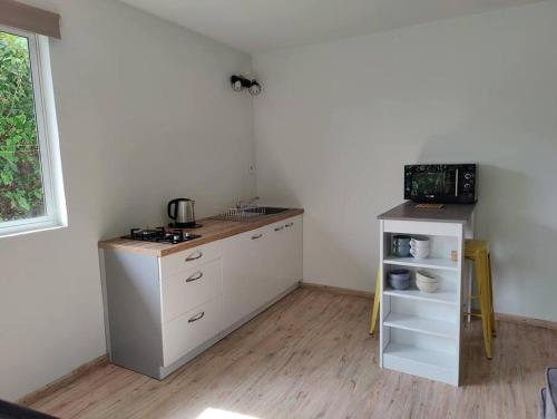 uma cozinha com armários brancos e uma bancada em Logement cozy avec Jardin em Arue