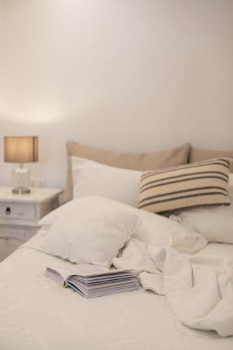 a white bed with a book on top of it at Levantes House Mykonos in Ano Mera