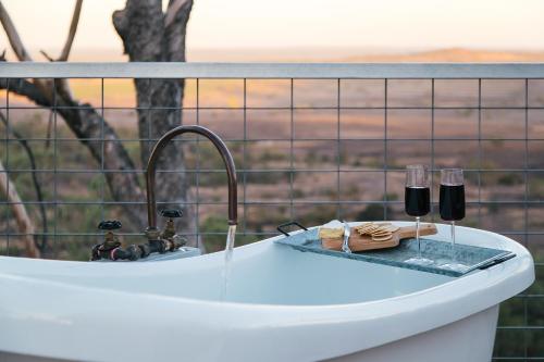 uma banheira com dois copos de vinho em cima em Faraway Domes em Warialda