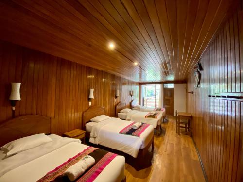 a group of four beds in a room with wooden walls at Mistico Machupicchu Eco B&B in Machu Picchu