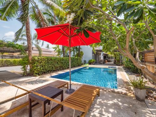 a red umbrella and a bench next to a swimming pool at Lemon House apartment in Koh Samui 