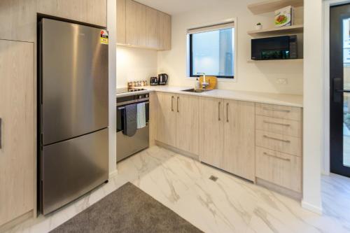 a kitchen with wooden cabinets and a stainless steel refrigerator at Wave side escape 1 bed 1 bath, New Brighton in Christchurch
