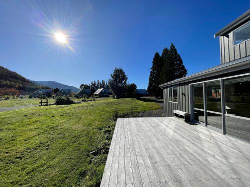 a house with a wooden deck next to a field at Pudding Hill Lodge & Chalets in Mount Hutt